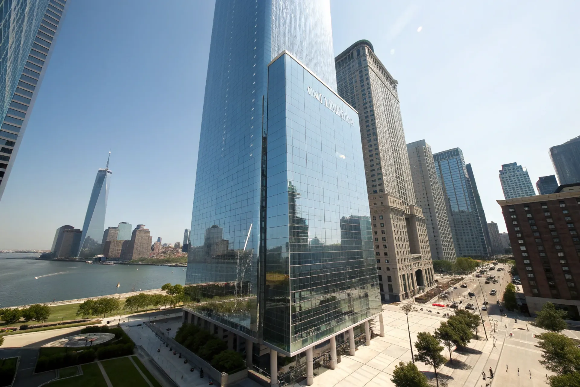 A modern skyscraper with a gleaming 3U nano-coated glass facade that reflects sunlight and repels dust, with the city skyline in the background.
