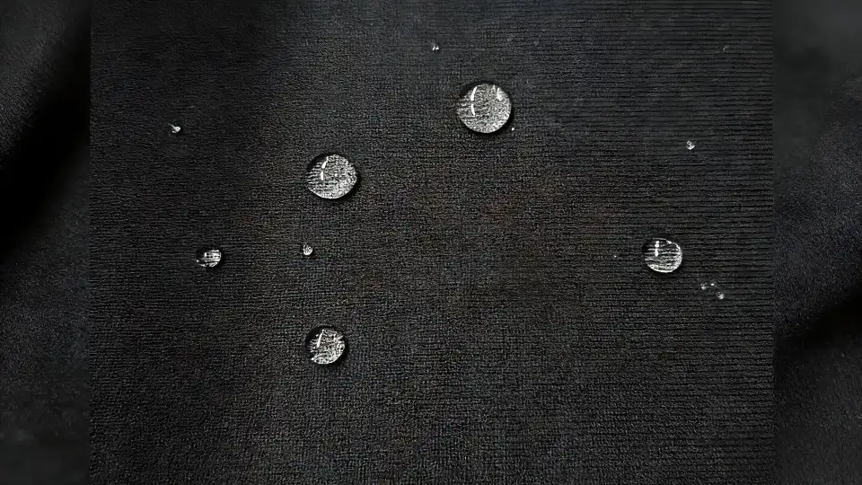 Water-repellent coating on fabric: Water droplets bead up on black textile, showing fluorine-free hydrophobic & stain-resistant performance